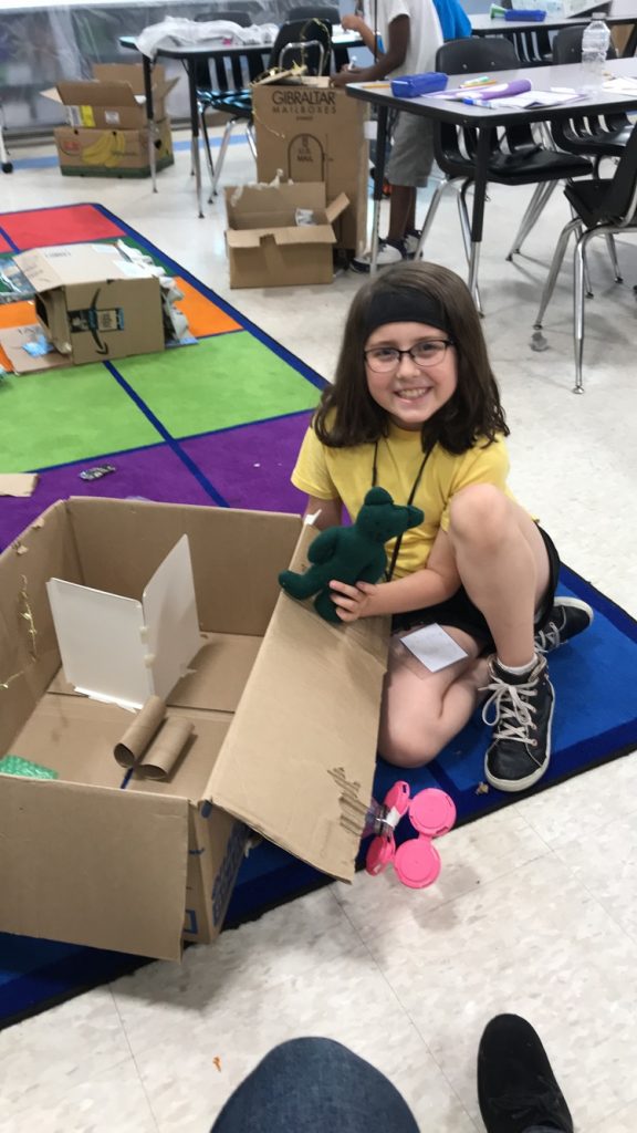(student Riley proud of her newly constructed Base she created for her Teddy Bear Astronaut)